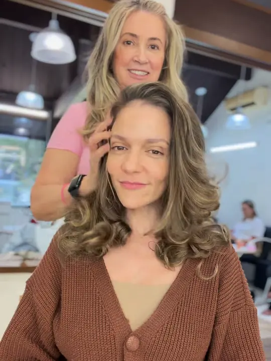 Cliente de cabelo castanho com mechas e ondas largas, em atendimento no Le Visage